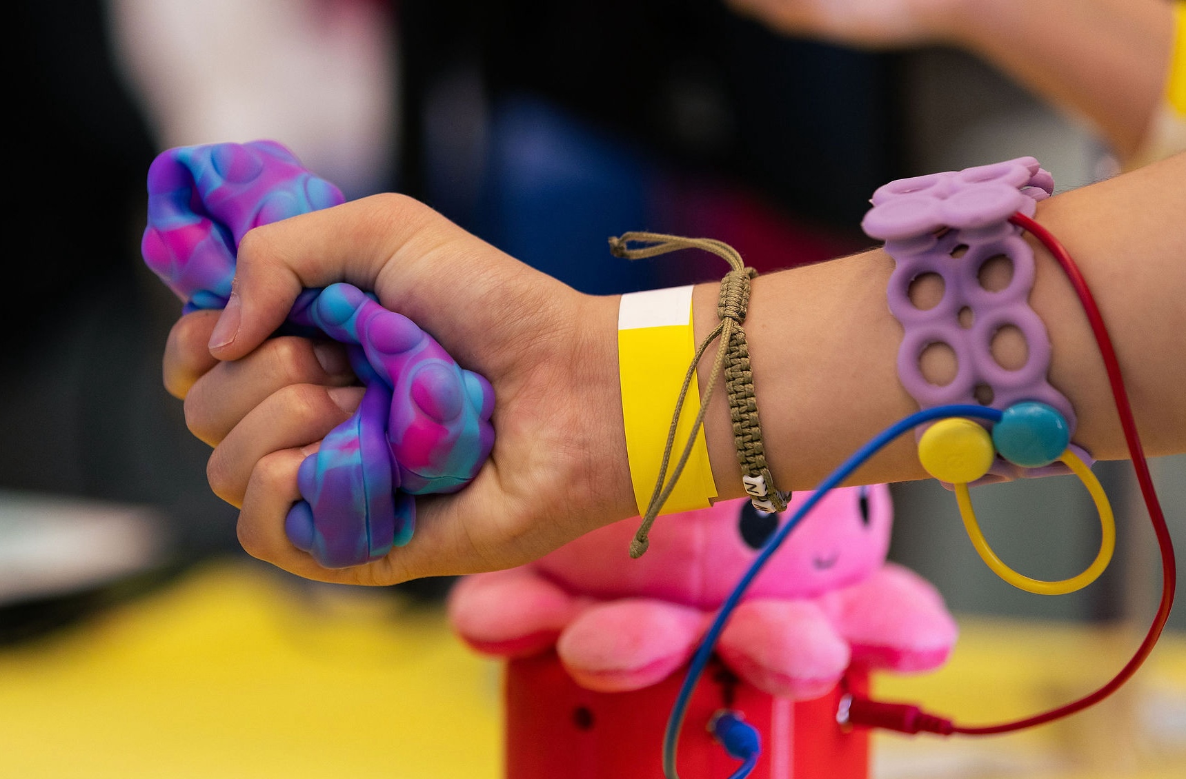 Person wearing a purple armband, squeezing a silicone object.